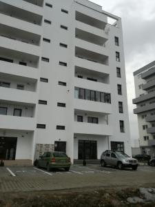 two cars parked in a parking lot in front of a building at White Luxury Apartment in Sibiu