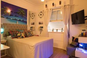 1 dormitorio con 1 cama, TV y ventana en Reformadíssimo na quadra praia de Copacabana Posto 6 na melhor localização do Rio - WiFi 500Mb, en Río de Janeiro