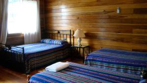 two beds in a room with wooden walls at Hotel Laguna in Bocas Town