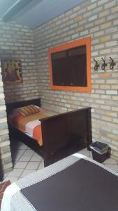 a bedroom with a bed and a tv on a brick wall at Chales Jack & Jill in Pipa