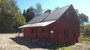 eine rote Scheune mit einem Metalldach auf einem Feld in der Unterkunft Casa del Rio in La Ensenada