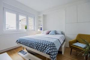 ザグレブにあるSweet & Petiteのベッドと椅子のある白い寝室