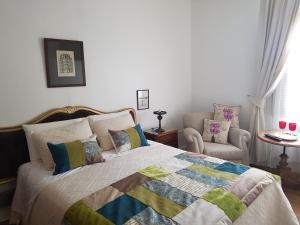 een slaapkamer met een bed en een stoel bij Casa Mackenna in Valparaíso