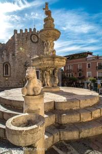 a large stone fountain in front of a castle at Taormina castle and sea view in Taormina