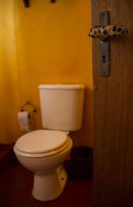 a bathroom with a white toilet in a yellow wall at Cabañas Bien al Este in Punta Del Diablo