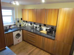 - une cuisine avec des placards en bois et un lave-linge dans l'établissement Farraline Court, à Inverness