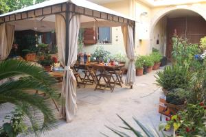 um pátio com um guarda-chuva, mesas e vasos de plantas em Fiori e Limoni em Quartucciu