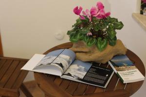 uma mesa com um livro e um vaso com flores em Fiori e Limoni em Quartucciu