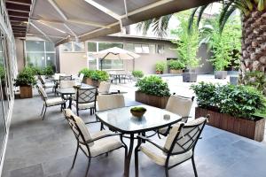 un patio con mesas, sillas y plantas en Hotel Boutique Raíces, en Curicó