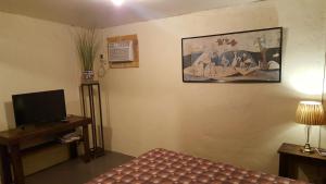 um quarto com uma cama, uma televisão e uma pintura em Marius B&B & Hostel em Silang