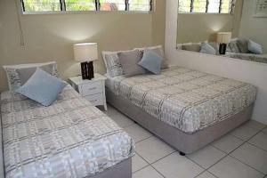 1 dormitorio con 2 camas y espejo en Lagoon Beachfront Lodge 005 on Hamilton Island by HamoRent, en Hamilton Island