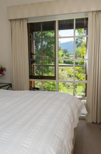 a bedroom with a bed and a large window at Hollyhock in Macedon