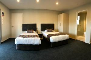 a hotel room with two beds in a room at Ellerslie Palms Motel in Auckland