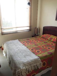 ein Schlafzimmer mit einem Bett mit einer bunten Decke in der Unterkunft Bahia Pelicanos in Horcón