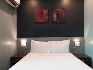 uma cama num quarto com duas pinturas na parede em Leez Inn Malate em Manila