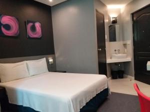 um quarto de hotel com uma cama e um lavatório em Leez Inn Malate em Manila