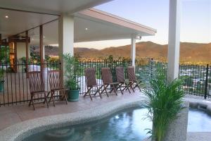 a patio with chairs and a swimming pool with mountains in the background at The Summit Rainforest Retreat in Atherton