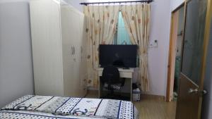 une chambre avec un lit et un bureau avec une télévision dans l'établissement Thuy Huong Homestay, à Hô-Chi-Minh-Ville 4 autres photos