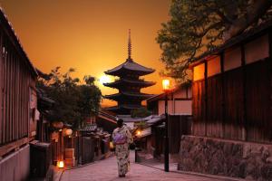 a woman walking down a street in front of a pagoda at Kyoto Inn Gion The Second in Kyoto