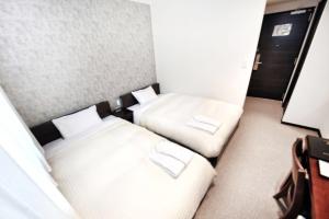 two beds in a small room with white pillows at Toho Hotel in Osaka