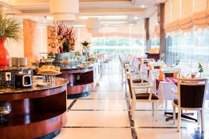 a restaurant with tables and chairs and a buffet at Dakruco Hotel in Buon Ma Thuot