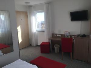 a hotel room with a desk and a table with red chairs at Landhotel Gasthof am Berg in Dornstadt +13 photos