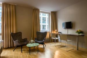 ein Hotelzimmer mit Stühlen, einem Tisch und einem Schreibtisch in der Unterkunft Scope Hotel City Stay Frankfurt in Frankfurt am Main