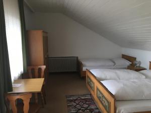 a room with two beds and a table and a desk at Landhotel Gasthof am Berg in Dornstadt