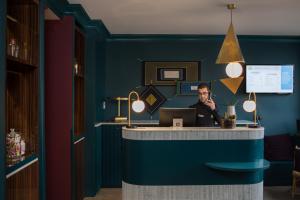 a man sitting at a desk with a laptop at ibis Styles Paris Nation Cours de Vincennes in Paris