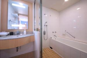 a bathroom with a tub and a sink and a shower at Laguna Garden Hotel in Ginowan