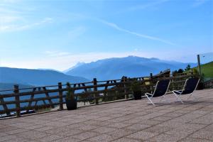 two chairs sitting on a patio with mountains in the background at SCHUPFE- direkt neben der Kabinenbahn Gitschberg Jochtal in Maranza