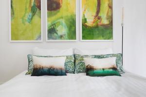 a white bed with two pillows and paintings on the wall at Romantic Artist Room Montmartre Bed & Breakfast in Paris