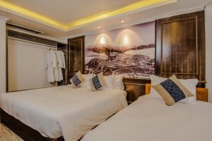 2 Betten in einem Hotelzimmer mit Wandgemälde in der Unterkunft Delta Sapa Hotel in Sa Pa