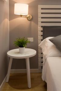 a table with a plant on it next to a bed at Suite Erica Lignano Hotel in Lignano Sabbiadoro