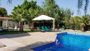 a swimming pool with an umbrella and a table and chairs at Chalet Bacarot in Alicante