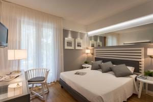 a bedroom with a large bed with a desk and a chair at Suite Erica Lignano Hotel in Lignano Sabbiadoro