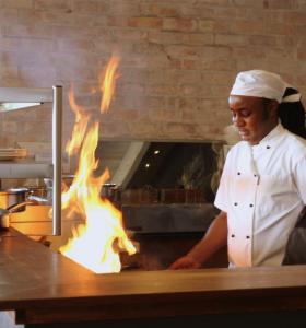 a chef preparing food in a kitchen with flames at The Quarter Deck in Kenton on Sea