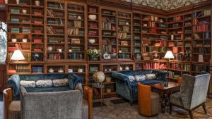 a library with two couches and a table and bookshelves at De Vere Tortworth Court in Wotton-under-Edge