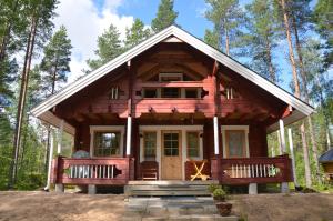 a log cabin in the woods with two benches at Villa Sarastus in Vaala