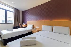 a hotel room with two beds and a chair at Signature Hotel @ Puchong Setiawalk in Puchong