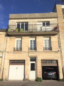 ein Gebäude mit einem Balkon und einem Auto vor dem Haus in der Unterkunft Coeur de Bastide in Bordeaux