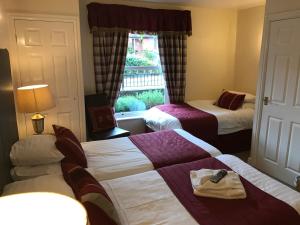 a hotel room with two beds and a window at Clayhanger Guest House in Newcastle under Lyme