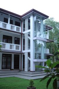 a large white building with a lawn in front of it at Gem Field Rest in Ratnapura