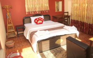Un dormitorio con una cama con una almohada roja encima. en Elbrus Home, en Katmandú