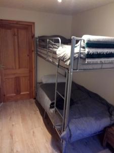a room with two bunk beds and a door at Pammy's Family Annexe EXCLUSIVE USE in Garve