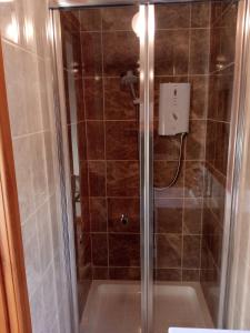 a shower with a glass door in a bathroom at Pammy's Family Annexe EXCLUSIVE USE in Garve