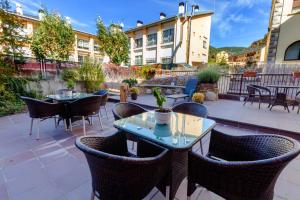 eine Terrasse mit Tischen und Stühlen und ein Gebäude in der Unterkunft Hotel Flor De Neu in El Pont de Suert