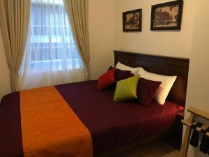 ヌワラエリヤにあるRegal Rose Luxury Holiday Apartmentsのベッドルーム1室(カラフルな枕と窓付)