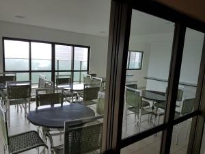 an empty room with tables and chairs and windows at Flat Gildo Vilaça in Recife
