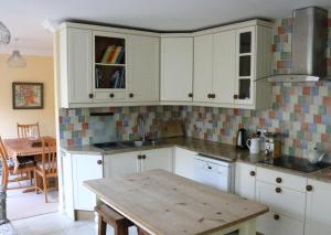 a kitchen with white cabinets and a wooden table at Tehidy Holiday Park in Illogan